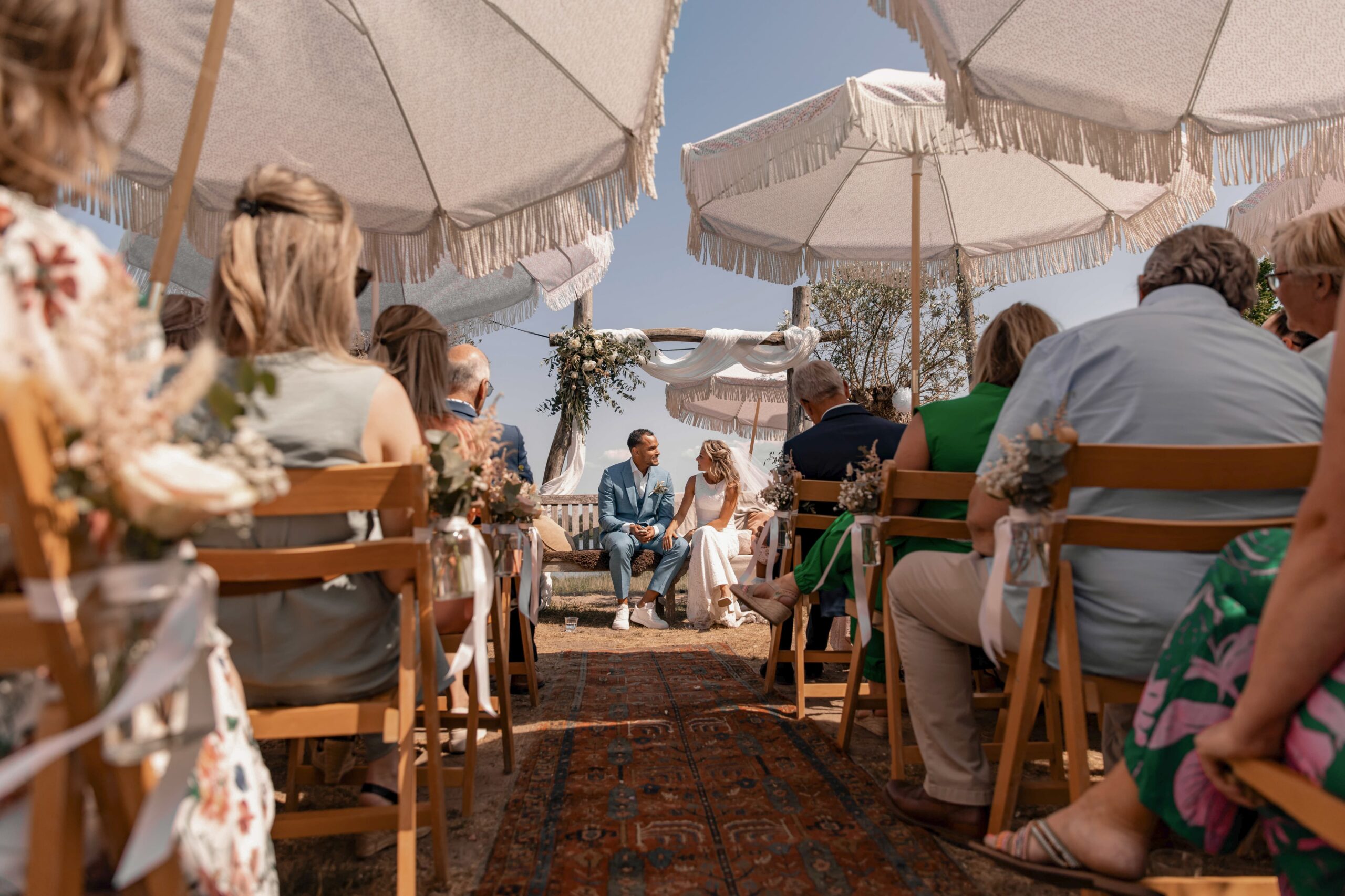 bruidspaar zit in een strandsetting bij de ceremonie van hun bruiloft