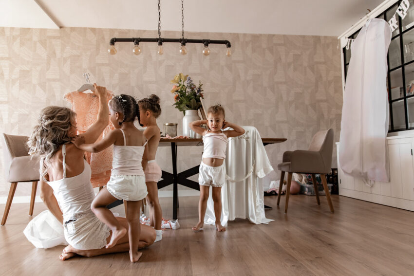 Trouwfotografie in Lisse, bruid kleedt haar dochters aan.
