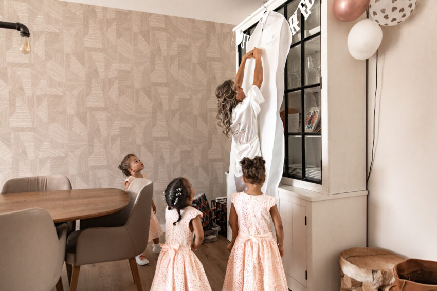 Trouwfotografie in Lisse, bruid trekt haar trouwjurk aan met haar drie dochters.
