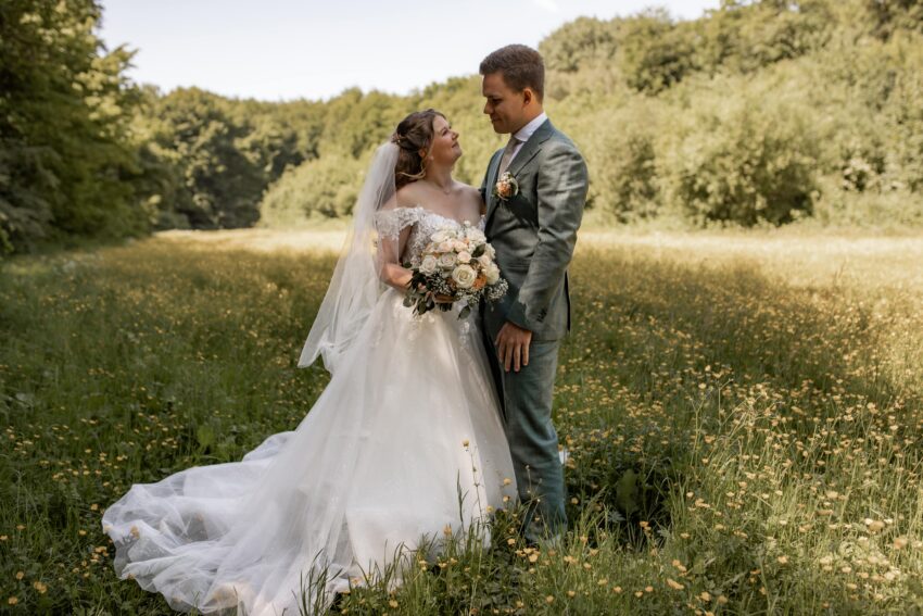 trouwfotograaf in het Amsterdamse Bos, bruidspaar staat midden in een prachtig veld met gele bloemen