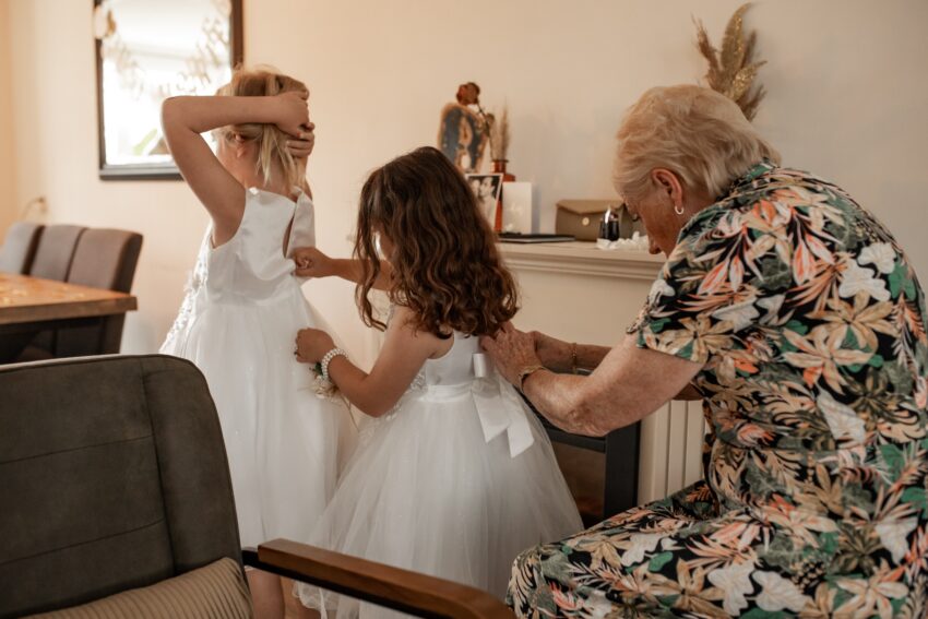 Trouwfotograaf in Kudelstaart, oma doet de jurk van haar kleindochter dicht